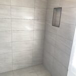 Black trim shower niche shelf in open porcelain tiled bathroom